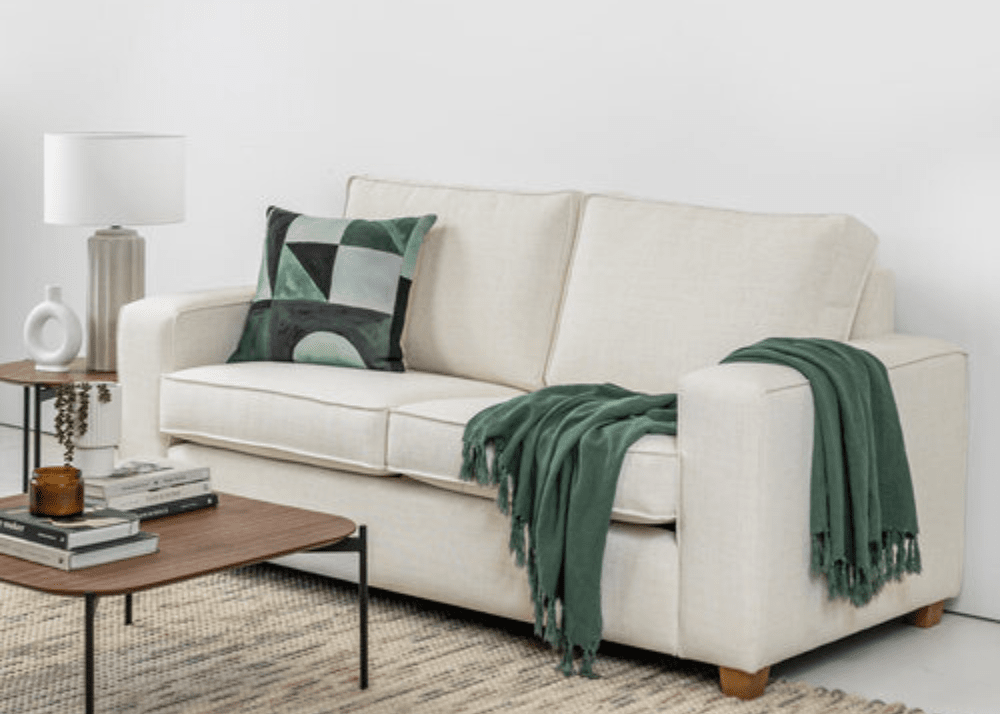 White sofa with green throw blanket and pillow in a living room setting